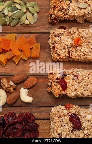 Différentes barres de granola savoureuses et des ingrédients sur la table en bois, à plat Banque D'Images