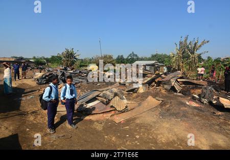 Dimapur, Inde : 13 novembre 2023 : passage des élèves de l'école entre la maison carbonisée après un enfer dans la nuit de Diwali, la fête hindoue de la lumière, qui a détruit au moins 50 maisons tuant 5 personnes à Naharbari à Dimapur, Inde, dans l'état nord-est du Nagaland. Crédit : Caisii Mao/Alamy Live News Banque D'Images