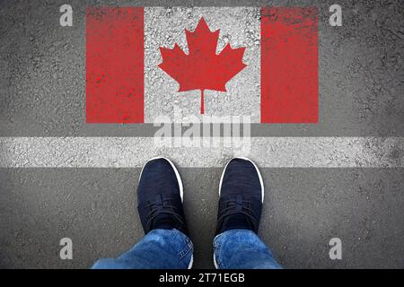 Immigration. Homme debout sur l'asphalte près du drapeau du Canada, vue de dessus Banque D'Images