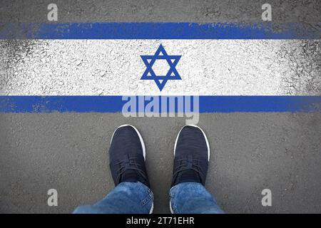 Immigration. Homme debout sur l'asphalte près du drapeau d'Israël, vue de dessus Banque D'Images