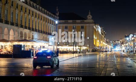 Une voiture de police roulant dans une rue la nuit Banque D'Images