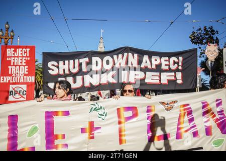 San Francisco, États-Unis. 12 novembre 2023. Les gens tiennent des banderoles et des pancartes pendant qu'ils marchent dans la rue. La coopération économique Asie-Pacifique (APEC) accueille son sommet 2023 à San Francisco, en Californie, du 11 au 17 novembre, principalement au Moscone Center. Le sommet attire des dirigeants et des représentants du monde des affaires de divers pays, qui participent à des discussions sur divers enjeux mondiaux. Cependant, le 12 novembre, une importante manifestation se déroule dans les rues de San Francisco, attirant des milliers de manifestants de divers groupes, y compris ceux qui militent pour le changement climatique et Banque D'Images