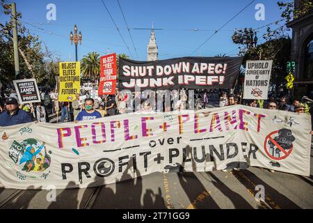 San Francisco, États-Unis. 12 novembre 2023. Les gens tiennent des banderoles et des pancartes pendant qu'ils marchent dans la rue. La coopération économique Asie-Pacifique (APEC) accueille son sommet 2023 à San Francisco, en Californie, du 11 au 17 novembre, principalement au Moscone Center. Le sommet attire des dirigeants et des représentants du monde des affaires de divers pays, qui participent à des discussions sur divers enjeux mondiaux. Cependant, le 12 novembre, une importante manifestation se déroule dans les rues de San Francisco, attirant des milliers de manifestants de divers groupes, y compris ceux qui militent pour le changement climatique et Banque D'Images