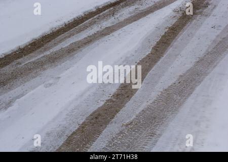 Pistes de voiture sur une route enneigée. Route glissante, danger, risque de dérapage. Traces de traces de pneus d'hiver. Banque D'Images