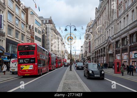 Nouveaux et anciens bus rouges et taxis noirs circulant le long du Strand à Londres. Novembre 2023 Banque D'Images