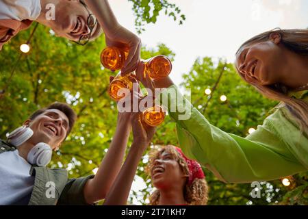 Amis heureux clinking bouteilles de bière vue du bas Banque D'Images