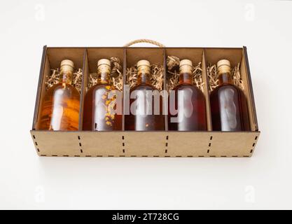 coffret cadeau de bouteilles avec whisky d'alcool brun et brandy. Teinture à base de plantes maison dans une boîte en bois sur fond blanc. Naturel Banque D'Images