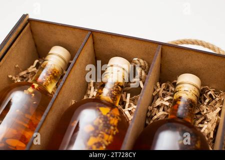 Bouteilles avec brandy de boisson alcoolisée maison chère et cognac dans une boîte en bois, gros plan. Banque D'Images