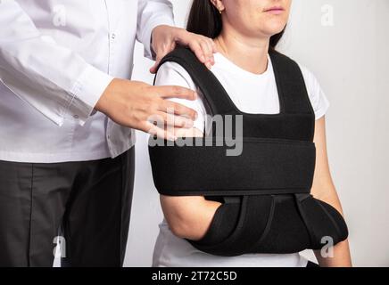 Un médecin chirurgien examine l'épaule d'une fille après l'opération. Bandage sur l'articulation de l'épaule pendant la rééducation après chirurgie sur l'articulation de l'épaule, te Banque D'Images