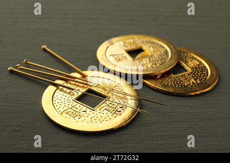 Aiguilles d'acupuncture et pièces chinoises antiques sur table en bois gris, gros plan Banque D'Images