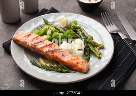 Repas sain. Morceau de saumon grillé, légumes, asperges et romarin servi sur une table texturée grise, gros plan Banque D'Images