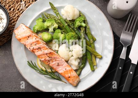 Repas sain. Morceau de saumon grillé, légumes, asperges et romarin servi sur une table texturée grise, plat Banque D'Images