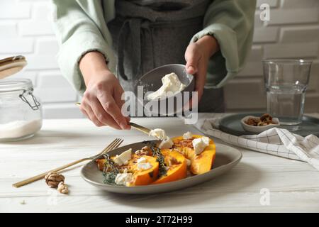 Femme mettant du fromage sur des tranches de citrouille cuites à table, gros plan Banque D'Images