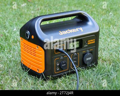 Jackery Explorer 500 centrale électrique portable debout sur l'herbe verte dans le jardin. La batterie est chargée par un panneau solaire. Énergie pour le camping. Banque D'Images