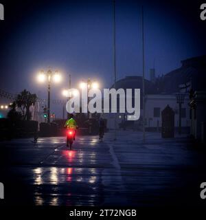 Un cycliste portant des vêtements de haute visibilité chevauchant le long de la promenade sous la pluie sur un Worthing Beach matin de novembre, Worthing, Royaume-Uni le 13 novembre 2023. Photo de Julie Edwards. Banque D'Images