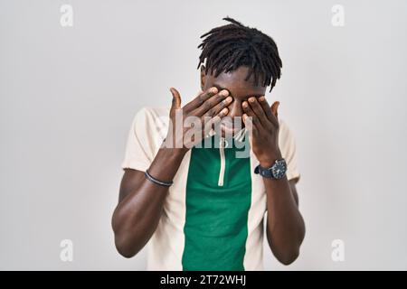 Homme africain avec des dreadlocks debout sur fond isolé frottant les yeux pour la fatigue et les maux de tête, somnolent et fatigué expression. problème de vision Banque D'Images