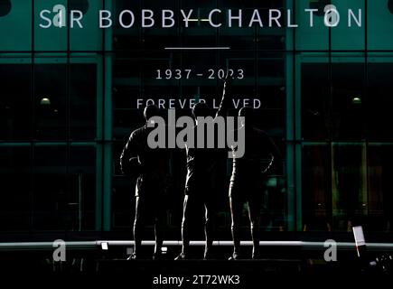 Une vue de la statue de la Trinité-Unie de Sir Bobby Charlton, Denis Law et George Best à l'extérieur d'Old Trafford à Manchester lors de la procession funéraire du grand Sir Bobby Charlton de Manchester United et d'Angleterre décédé à l'âge de 86 ans en octobre. Charlton marque 249 buts pour Manchester United et les aide à remporter trois titres de champion, une FA Cup et la coupe d'Europe en 1968. Au niveau international, il fait partie de l'équipe d'Angleterre qui remporte la coupe du monde en 1966. Date de la photo : lundi 13 novembre 2023. Banque D'Images