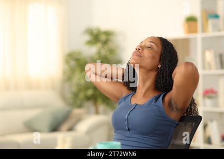 Femme noire reposant assise sur une chaise à la maison Banque D'Images