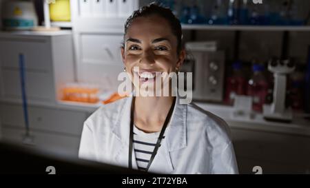 Confiante et belle jeune scientifique hispanique, souriante exubérante tout en immergeant dans la recherche médicale révolutionnaire, travaille assidûment uedn Banque D'Images