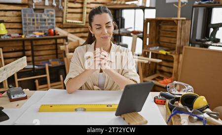 Jeune belle femme hispanique charpentier utilisant le touchpad à la menuiserie Banque D'Images