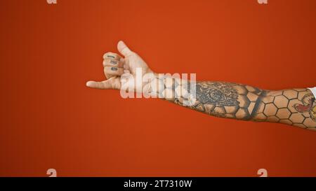 Beau geste de surf d'homme tatoué, ok pouce vers le haut de l'approbation sur un fond rouge isolé Banque D'Images