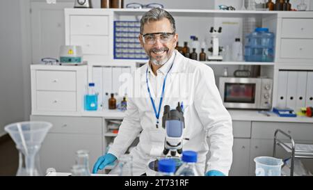 Un jeune homme hispanique confiant, un scientifique aux cheveux gris avec un sourire charmant, manipule magistralement un microscope dans un laboratoire animé, énergiquement absorbé Banque D'Images