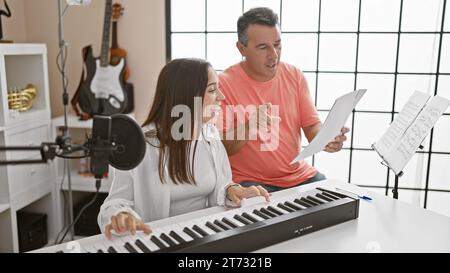 Des musiciens souriants, hommes et femmes, se sont imprégnés de leur leçon de studio de musique, harmonisant les mélodies sur piano acoustique tout en chantant ensemble Banque D'Images