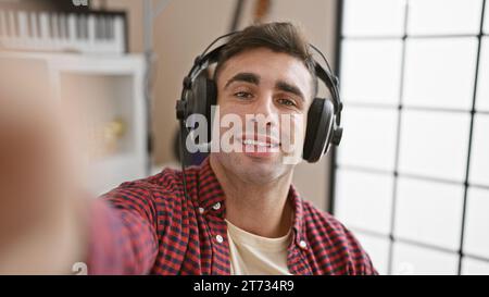 Jeune musicien hispanique confiant, artiste jouant à l'intérieur, écoutant avide la mélodie, parlant passionnément sur appel vidéo dans le studio de musique Banque D'Images