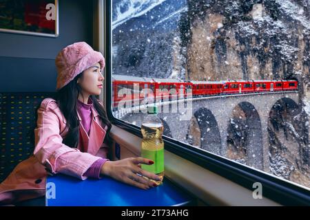 Touriste regardant par la fenêtre profitant avec train passant à travers la célèbre montagne à Filisur, Suisse. Landwasser Viaduc patrimoine mondial avec tra Banque D'Images