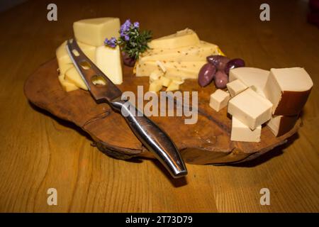 Une assiette à fromage en bois avec trois types de fromages et olives différents, Banque D'Images