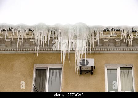 D'énormes morceaux de glace suspendus à l'avant-toit des bâtiments menaçant de s'effondrer pendant le dégel Banque D'Images