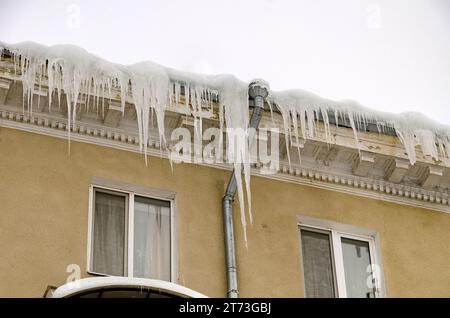 D'énormes morceaux de glace suspendus à l'avant-toit des bâtiments menaçant de s'effondrer pendant le dégel Banque D'Images