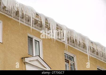 D'énormes morceaux de glace suspendus à l'avant-toit des bâtiments menaçant de s'effondrer pendant le dégel Banque D'Images