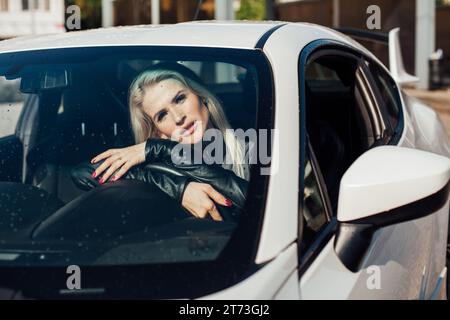 femme conductrice au volant d'une voiture blanche Banque D'Images