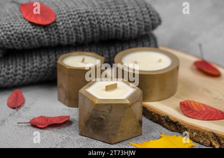 Bougies en pots dorés et feuilles rouges d'automne, composition minimale. Le concept de la chaleur et du confort à la maison Banque D'Images