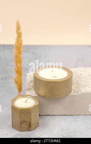 Bougies décoratives dans des pots dorés sur un podium en pierre naturelle, composition minimale Banque D'Images