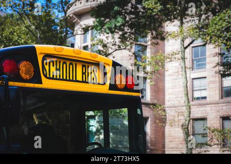 Gros plan de l'avant d'un autobus scolaire jaune américain traditionnel avec un grand panneau et des lumières de sécurité dans un environnement urbain Banque D'Images