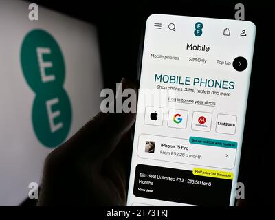 Personne tenant un smartphone avec une page Web de la société de télécommunications britannique EE Limited devant le logo. Concentrez-vous sur le centre de l'écran du téléphone. Banque D'Images