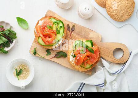 Sandwichs ouverts au saumon fumé avec fromage à la crème, concombre, graines de sésame, microgreens, épinards, et les feuilles de pois sur fond de bois vieux clair. Sain Banque D'Images