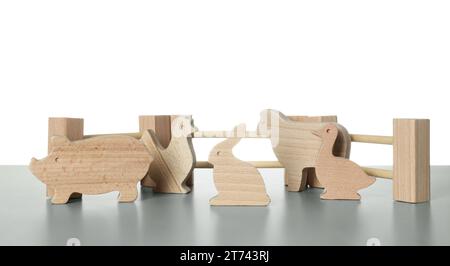 Ensemble d'animaux en bois et clôture sur table gris clair sur fond blanc. Jouet pour enfants Banque D'Images