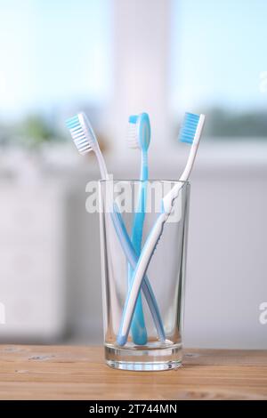 Brosses à dents en plastique dans le support sur la table en bois Banque D'Images