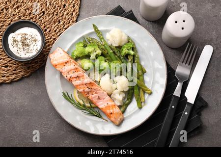 Repas sain. Morceau de saumon grillé, légumes, asperges et romarin servi avec sauce sur table texturée grise, plat Banque D'Images