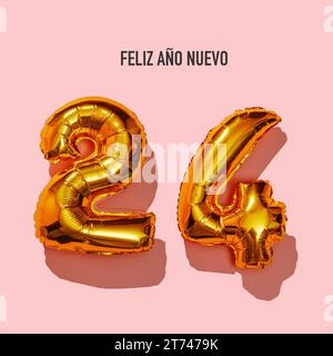le texte happy new year écrit en espagnol et deux ballons dorés en forme de nombre formant le numéro 24, sur fond rose Banque D'Images