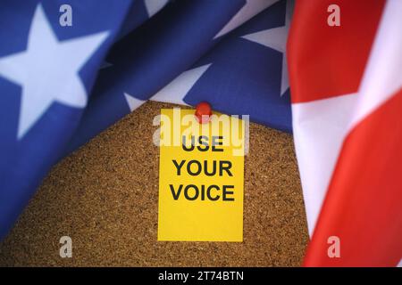 Le drapeau des États-Unis et la note de papier jaune avec le slogan utilisez votre voix dessus épinglés à un panneau de liège. Gros plan. Banque D'Images