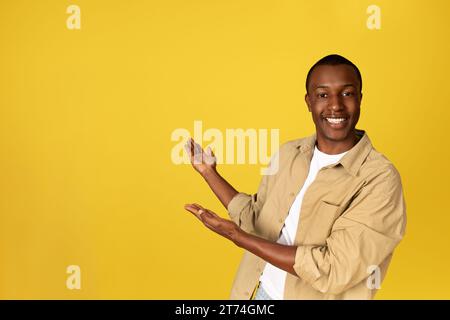 Positif jeune homme afro-américain étudiant dans les mains de point occasionnel à l'espace de copie Banque D'Images