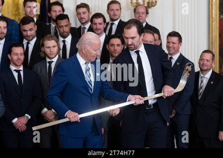 Le président des États-Unis Joe Biden reçoit un bâton de hockey plaqué or du capitaine Mark Stone lors d'une cérémonie d'accueil des Golden Knights de Vegas à la Maison Blanche à Washington, DC, pour célébrer leur victoire en coupe Stanley 2023 le lundi 13 novembre 2023. Crédit : Chris Kleponis/CNP/MediaPunch Banque D'Images