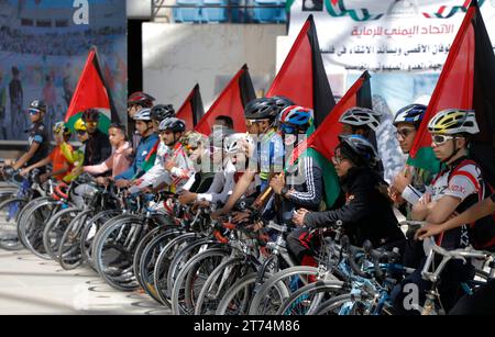 Des Yéménites brandissent des drapeaux palestiniens, dansent et font du vélo lors d'une veillée de solidarité avec le peuple palestinien, à Sanaa, Yémen, le 13 novembre 2023. Des milliers d’Israéliens et de Palestiniens sont morts depuis que le groupe militant Hamas a lancé une attaque sans précédent contre Israël depuis la bande de Gaza le 07 octobre et depuis les frappes israéliennes contre l’enclave palestinienne. Banque D'Images