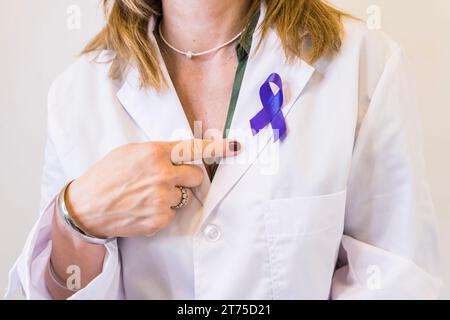 Femme médecin portant un ruban de sensibilisation au cancer tout en le pointant. Banque D'Images