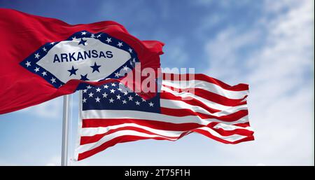 Les drapeaux de l'Arkansas et des États-Unis ondulent ensemble, symbolisant l'unité de l'État et de la nation contre un ciel bleu rayé de nuages Banque D'Images