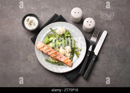 Repas sain. Morceau de saumon grillé, légumes, asperges et romarin servi avec sauce sur table texturée grise, plat Banque D'Images